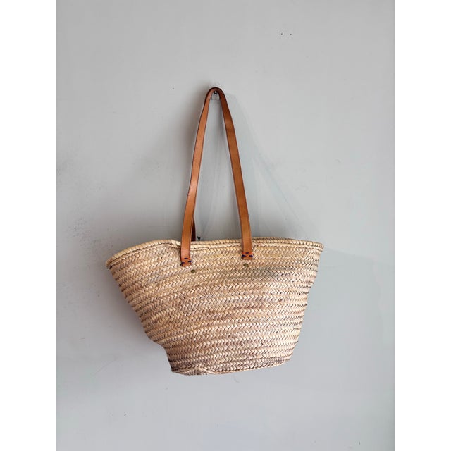 This appears to be a handwoven straw basket tote featuring a large bow made from colorful print Ankara fabric and brown...