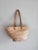 This appears to be a handwoven straw basket tote featuring a large bow made from colorful print Ankara fabric and brown...