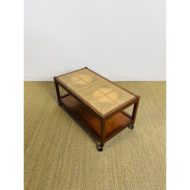Elegant vintage serving cart on casters, typical of 1960s scandinavian design. its frame is made of solid and veneered...