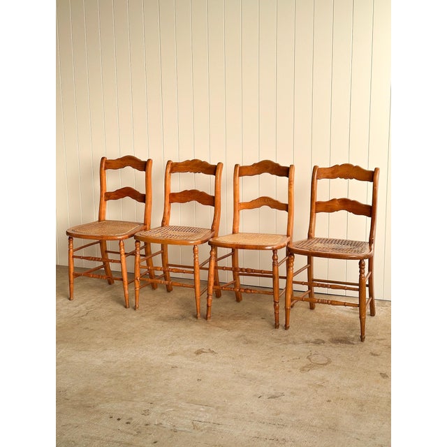 Set of four antique wooden dining chairs with ladder-back frames and woven cane seats. Solid hardwood construction with...