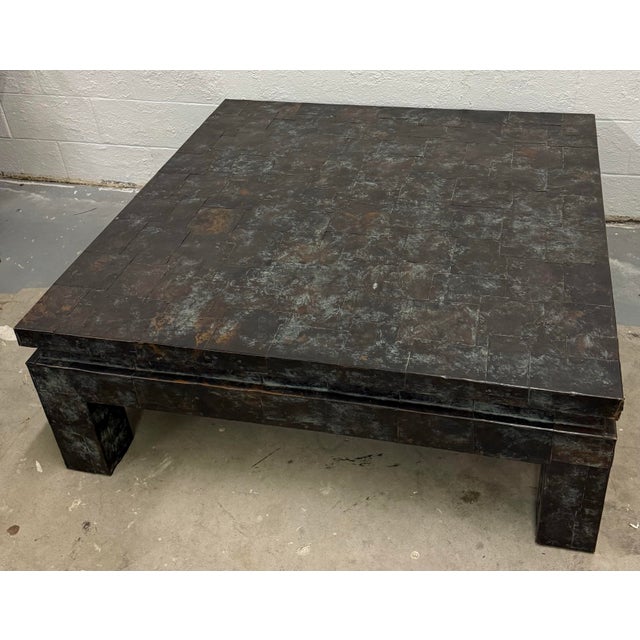 A monumental coffee table consisting of a patchwork design with copper square pieces attached to the wooden frame with...