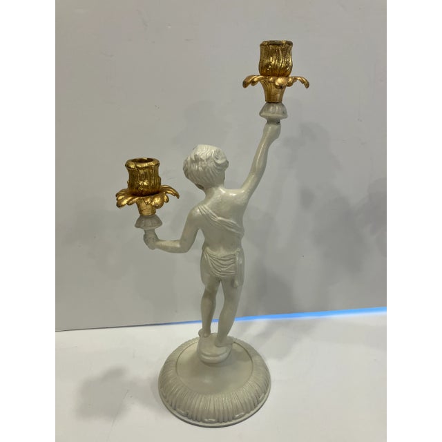 This pair of figural iron candelabra is painted ivory & gold Height 15.25 Width 8 Base diameter 5.5