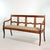A walnut bench with a straight crest rail above an open back divided by paired vertical supports and four scalloped...