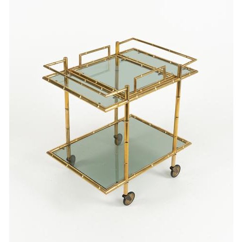 Midcentury amazing serving bar cart in a brass structure with bamboo effect and smoked glass shelves, the upper one...