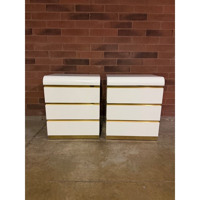 Pair of 1980s Postmodern Waterfall White Lacquer & Gold Nightstands Exceptional vintage postmodern waterfall nightstands...