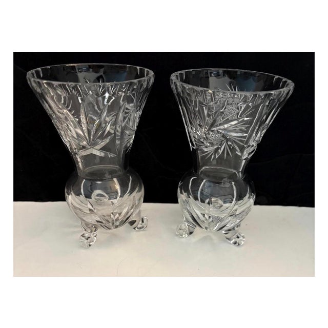 A sculptural pair of vintage cut crystal bud vases featuring crisp starburst and fan-cut detailing with sculptural tripod...