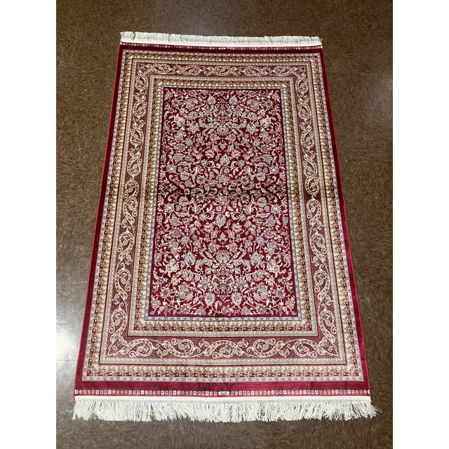 Machine-made Turkish wool rug featuring an all-over floral design set on a rich red field. The composition includes...