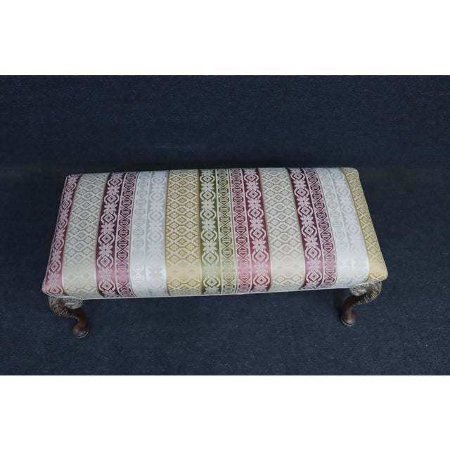 Queen Anne style upholstered bench in cherry wood. Features cabriole legs with carved and gilt-accented detailing and a...