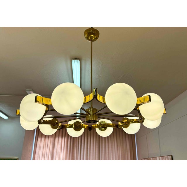 Elegant Italian chandelier handcrafted in Murano, featuring ten white Murano glass spheres arranged in a refined circular...