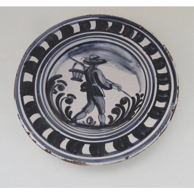 Delightful hand painted plate with scene of farmer. Measures 9 1/4" diameter. Has glaze wear to edge.