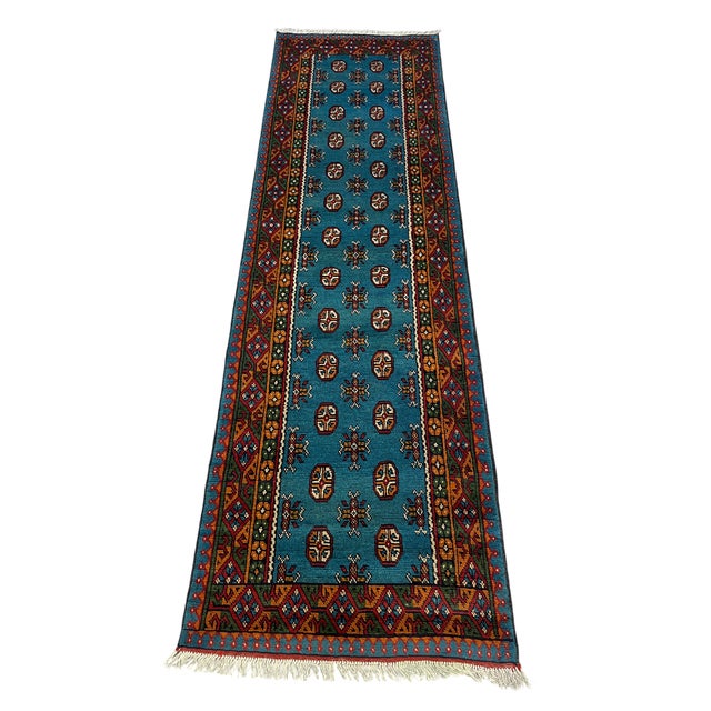 A rich blue field gives this tribal runner a striking backdrop for rows of repeating octagonal medallions and small...