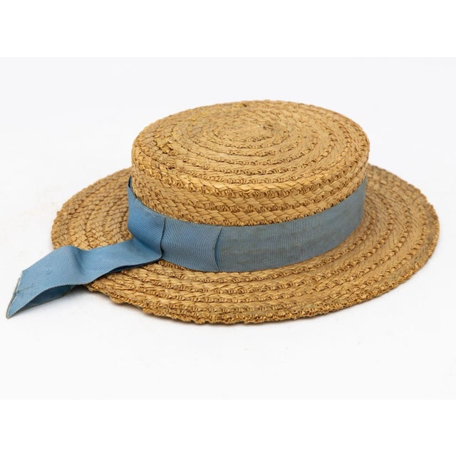 The Ridgemont Make's vintage 1930s boater hat showcases timeless elegance with its natural straw construction. Adorned...