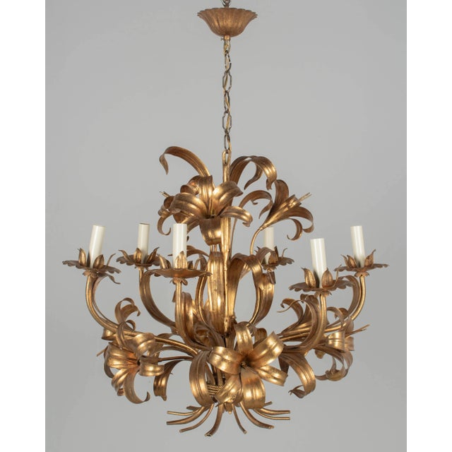 A Hollywood Regency style six-light gilt metal chandelier with tôle lily flowers. Original canopy and chain. Designed by...