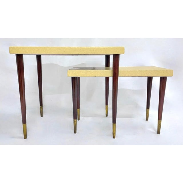 Set of two vintage Mid-Century Modern Paul Frankl cork top nesting side tables with tapered wood legs and brass feet....