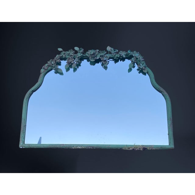 Beautiful mirror with wood frame, on the atop it has a metal flower garland