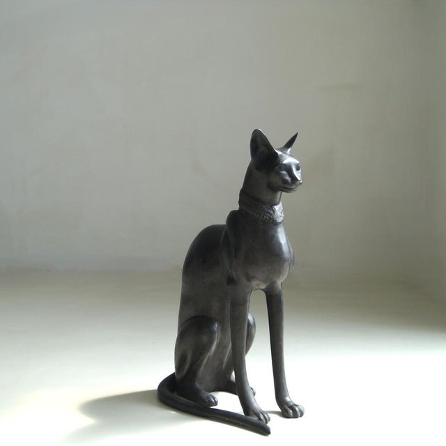A large and heavy Egyptian Revival cat, cast in a dark-patinated bronze alloy, modeled in the manner of the ancient Bastet...
