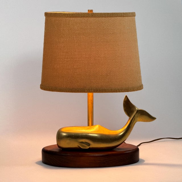 Vintage 1970s brass whale table lamp with a substantial sculptural whale form mounted on an oval wood base. The whale...