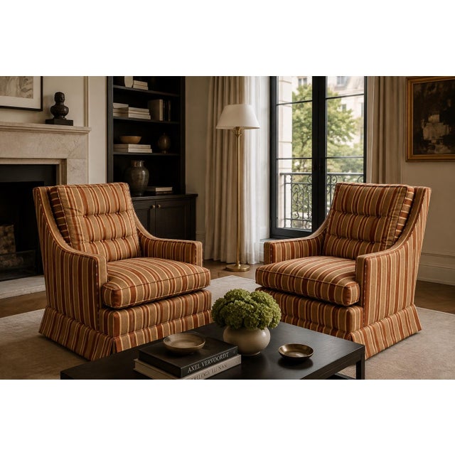 A pair of vintage club chairs upholstered in a brown, rust, and beige vertical striped fabric. The chairs feature tufted...
