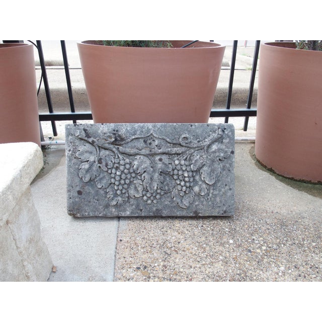 Hand-carved in Italy, this limestone plaque depicts a bas-relief display of grape clusters hanging from a vine with large...