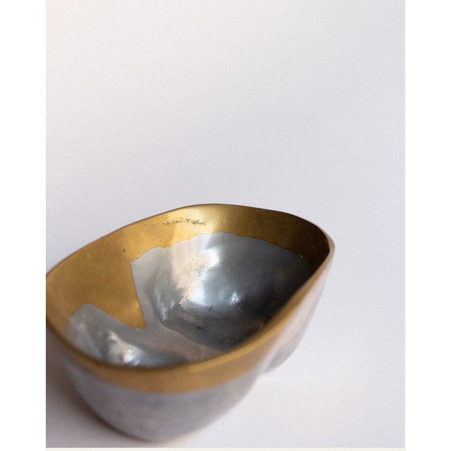 A cast metal empty-pocket by David Marshall, defined by a low, sculptural form and a clear horizontal division in...