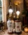 pair of vintage Chinoiserie porcelain table lamps with hand-painted floral motifs and wooden bases. • Left Lamp: Features...