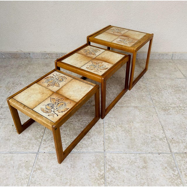 Set of three vintage nesting tables, typical of 1960s design. the frame is made of solid wood with a light honey hue,...
