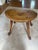 Solid wood stool featuring a distinctive sculpted triangular seat with a central elongated slot handle and four turned...