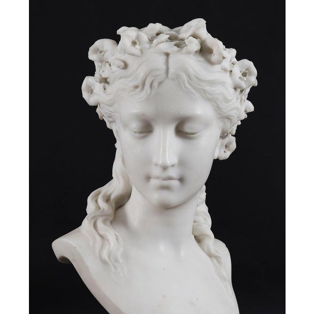 A beautifully sculpted Italian solid white Carrara marble bust sculpture of a Grecian Lady wearing a floral garland,...