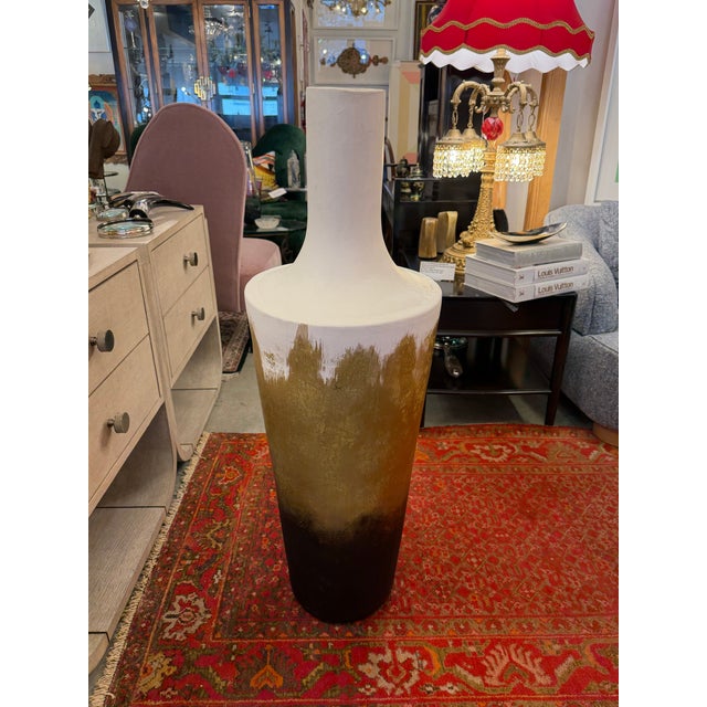 Tall vessel or urn handmade with plaster and other sculpting materials. The vessel is white with gold leaf, painted and...