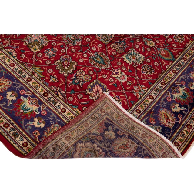 Beautiful vintage Persian Tabriz hand-knotted wool rug with a red color field. This piece has a blue frame and multicolor...