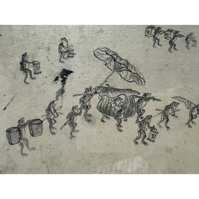 Charming Japanese ink drawing depicting a whimsical procession of anthropomorphic frogs carrying baskets, lantern-like...