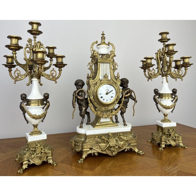 A magnificent antique louis xv garniture set featuring an elegant mantle clock with its matching pair of original...