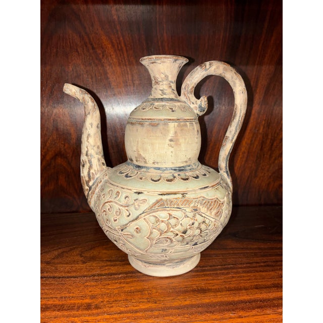 This vessel is a 15th century ceramonial Thai ewer with incised carp eating water lilly's culturally associated with...