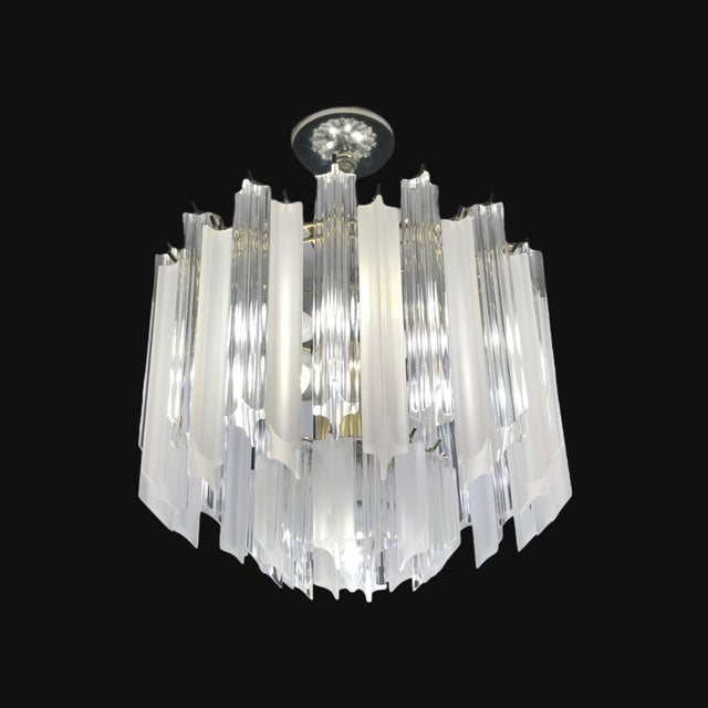Mid-Century Modern chandelier with frosted and clear Lucite prisms. In working condition; it uses 9 chandelier bulbs....