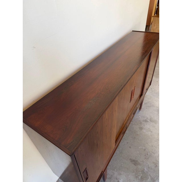 Impressive Danish Mid Century Modern rosewood sideboard featuring sliding doors, multiple interior shelving compartments,...