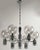 Six arm chandelier combines chrome plated metal and cast chrome plated relief. Cylinders at the center and on each arm are...