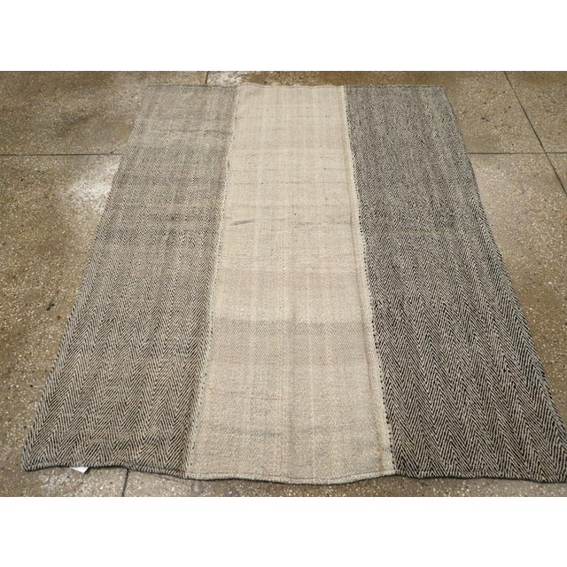 This Mid-20th century Turkish Flatweave Kilim rug, presents a bold yet understated design composed of three vertical...