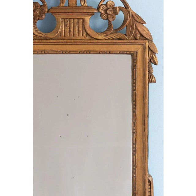 This exquisite early 18th-century French giltwood mirror features a rectangular frame adorned with a delicate frieze of...