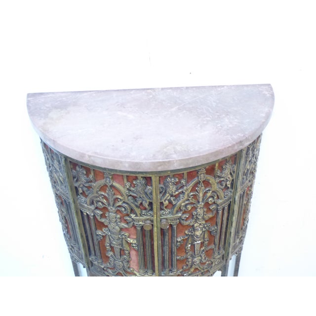 This gray marble top demi-lune metal cabinet has detailed metal work over old velvet background.