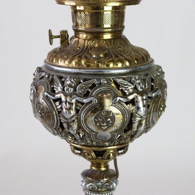 An antique American Victorian figural table lamp, crafted circa 1890, showcasing a harmonious blend of brass and silver-...