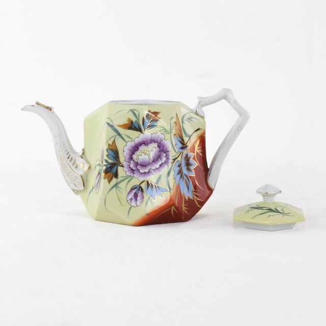 This exquisite antique porcelain teapot showcases a beautifully hand-painted floral design in rich purples, blues, and...