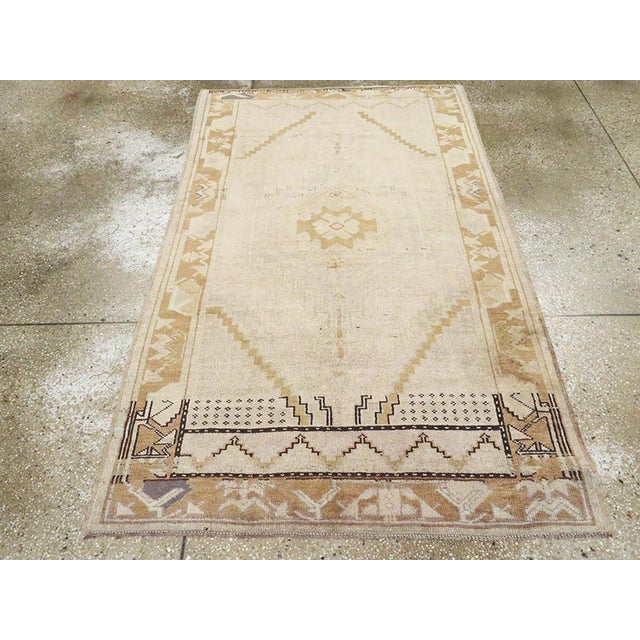 A vintage Turkish Oushak accent rug. This basically open field beige and rust Anatolian scatter has an Art Deco look in...