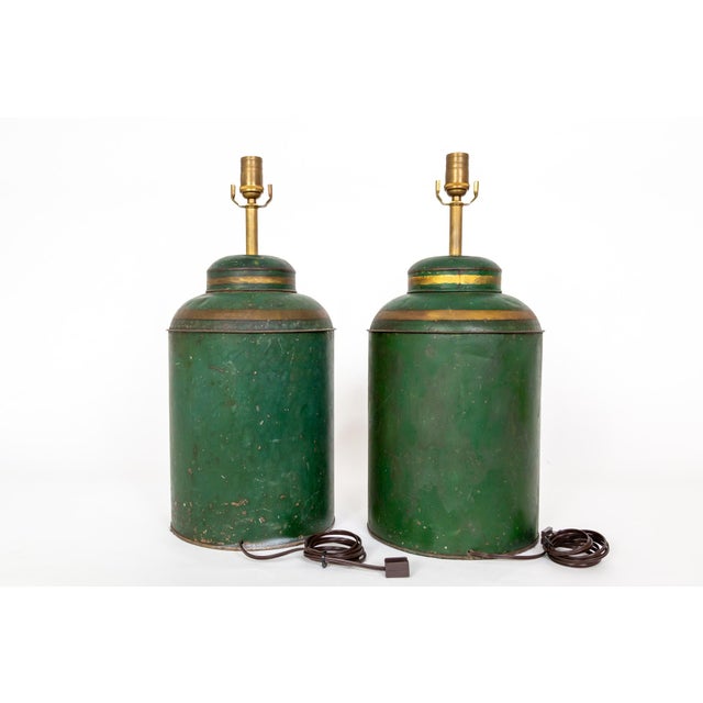 A pair of late 1800s tole tea tin canisters made into table lamps. They are green with gold trim and finely hand-painted...