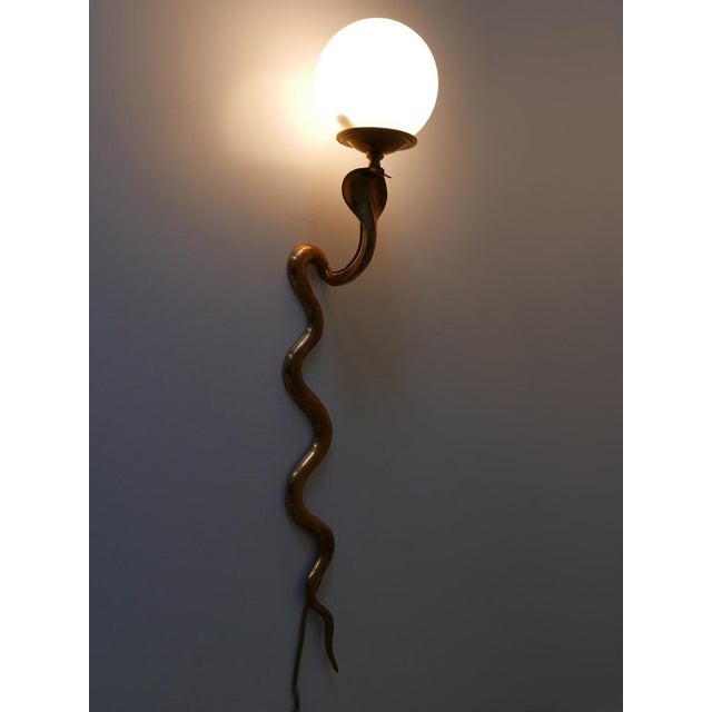 Rare and elegant mid-century modern cast brass cobra sconce or wall lamp. Designed and manufactured probably by maison...