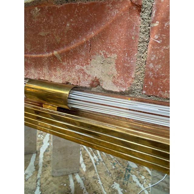 Elegant Italian mid-century wall mirror crafted in the 1970s, featuring a polished brass frame accented with fluted Lucite...