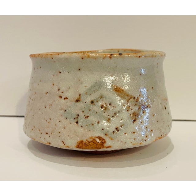 Japanese tea bowl with underglaze diamond shaped decoration. The bowl is footed with angled sides and a flared rim....