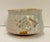 Japanese tea bowl with underglaze diamond shaped decoration. The bowl is footed with angled sides and a flared rim....