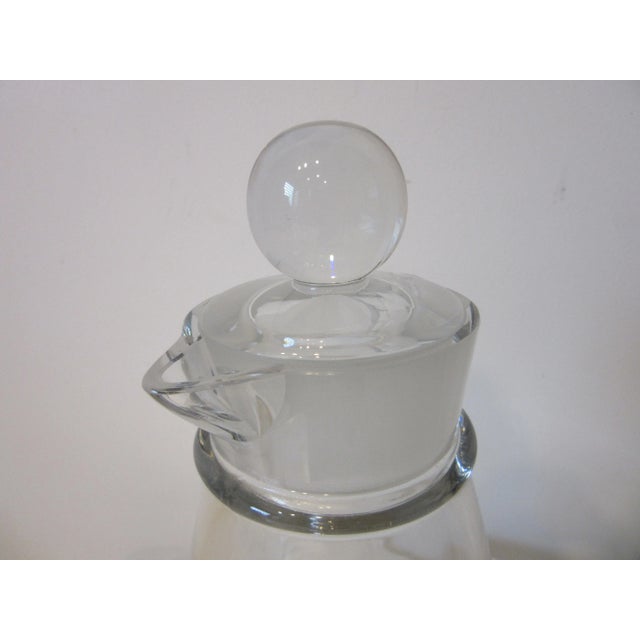 A very modern looking early heavy glass cocktail shaker with round ball top , frosted edge to the collar with two pour...