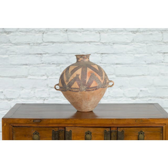 A Neolithic Chinese terracotta storage jar from 4000-3000 BC, with brown painted geometric decor and petite handles. Hand-...