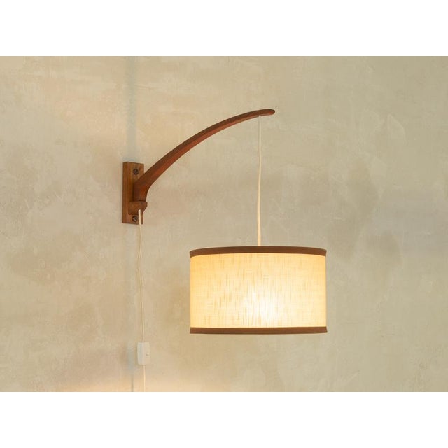 Beautiful wall lamp from the 1960s in scandinavian design. Swiveling teak frame with a beige lampshade and e27 socket....